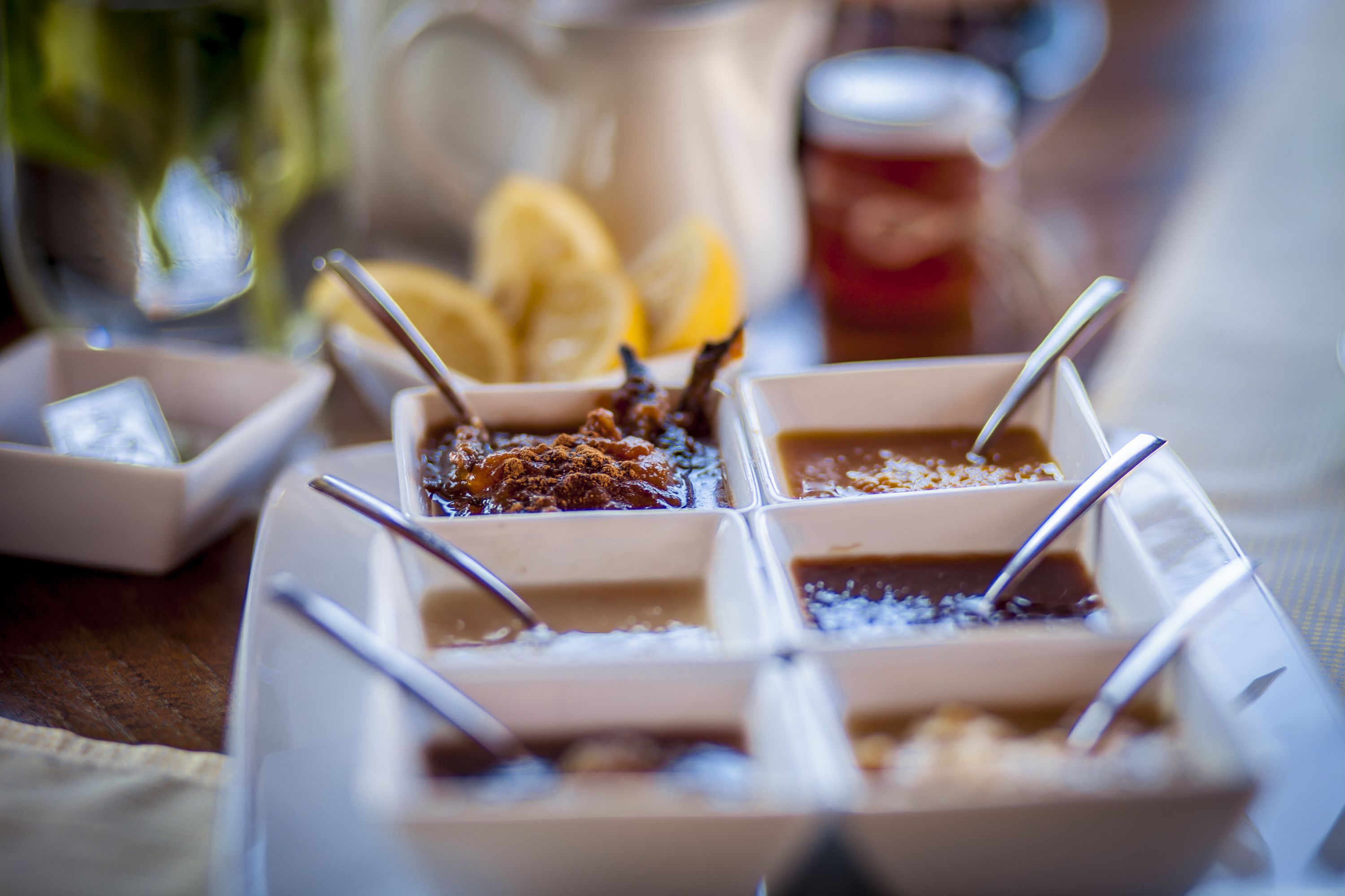 Una bandeja con diferentes salsas y aderezos, cucharas, una jarras y cuñas de limón sobre una mesa.