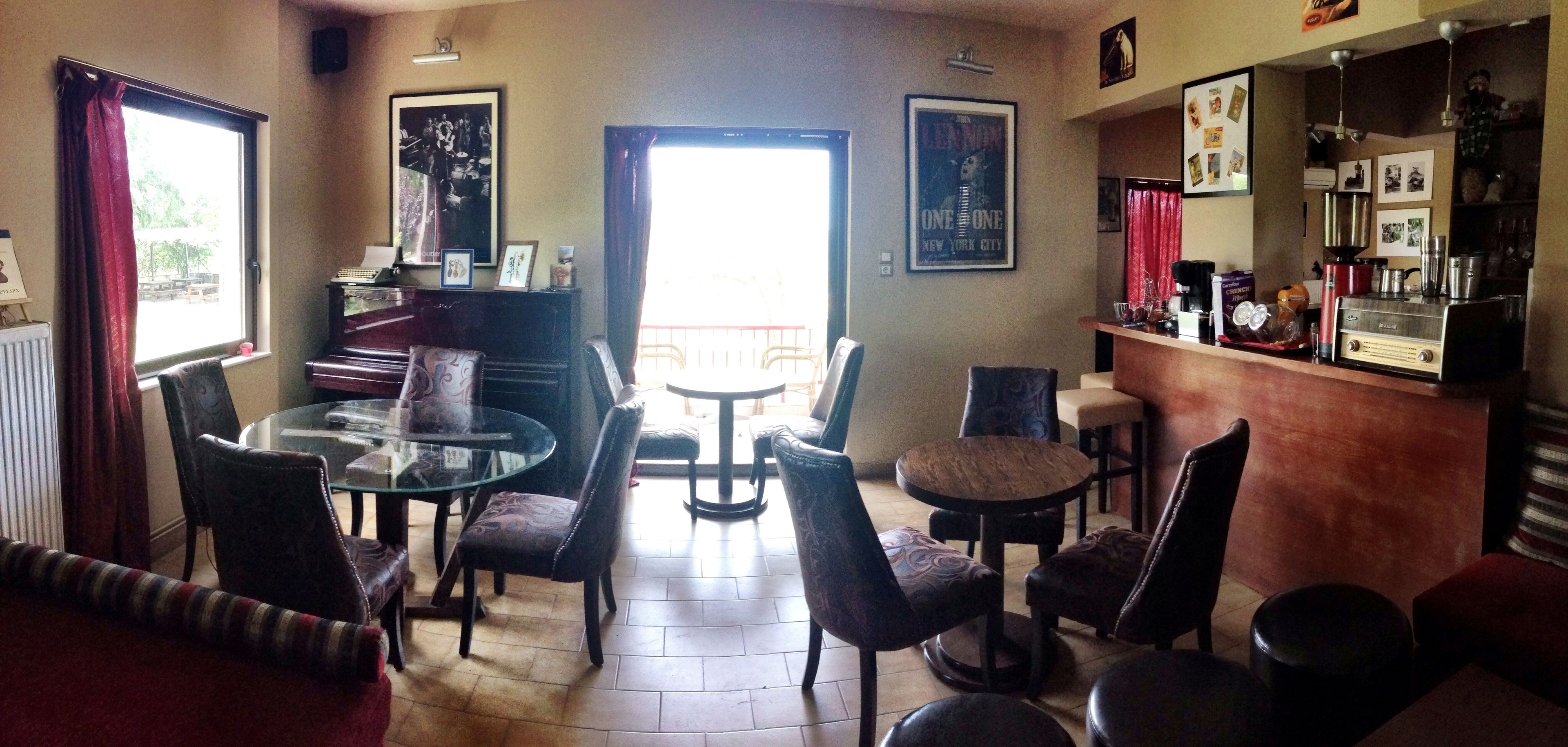 A cozy living room with a glass table, leather chairs, a piano, and a coffee bar with various items.