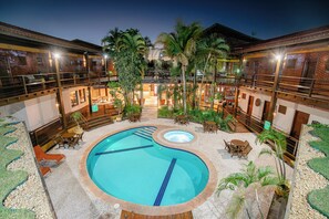 An outdoor swimming pool surrounded by lounge chairs and palm trees, with a building in the background. - Hotel Pirá Miúna (Bonito)