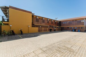 Um pátio com um edifício amarelo, uma parede de tijolos e um chão de azulejos.