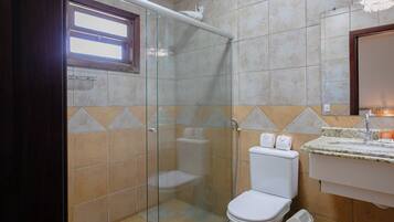 Een badkamer met een glazen douchecabine, toilet en een wastafel met een granieten aanrecht.