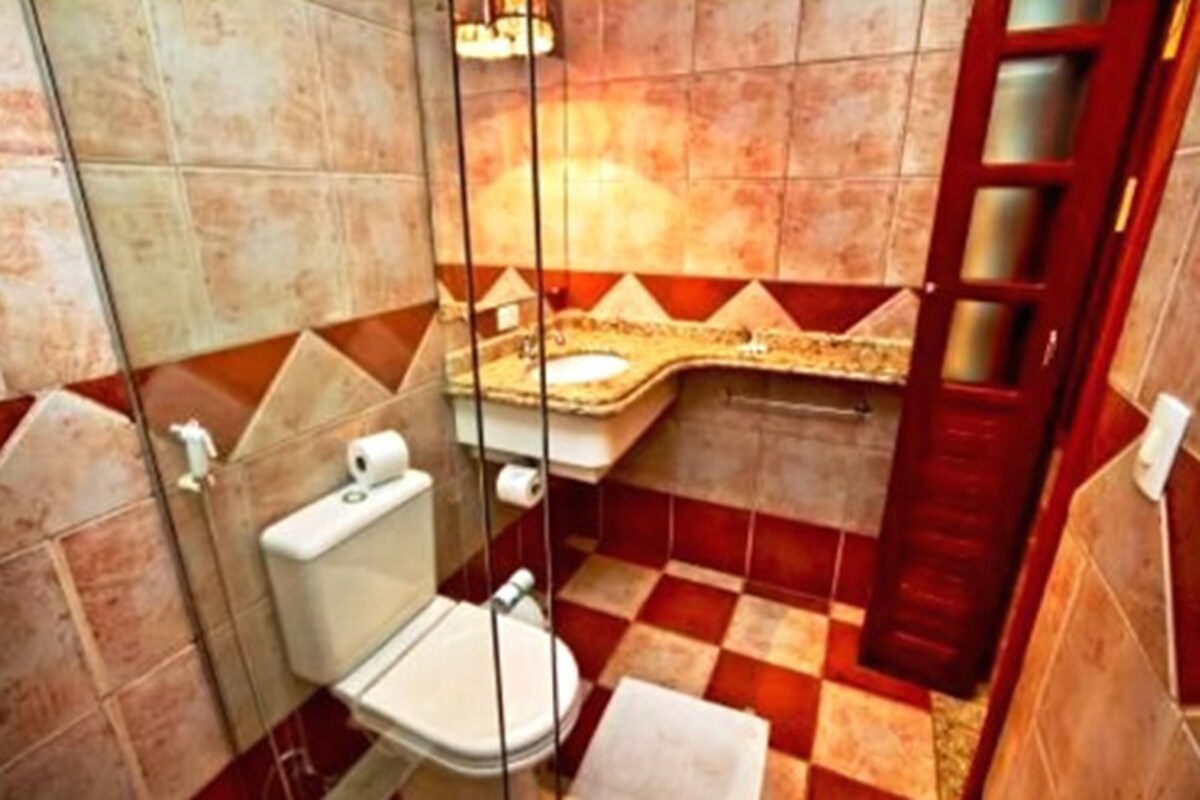 A bathroom with a toilet, a sink, and a shower area.