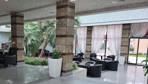 A spacious lobby with a seating area, large pillars, and a view of palm trees. - Detelina (Varna)