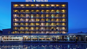 A multi-story hotel with balconies, a pool, and outdoor seating. - Detelina (Varna)