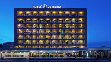 A multi-story hotel with balconies, a pool, and outdoor seating.