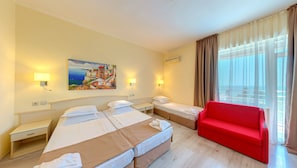 Una habitación de hotel con una cama grande, un sofá rojo, un cuadro en la pared y una ventana con cortinas.