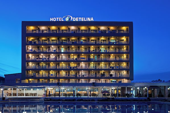 Ein mehrstöckiges Hotel mit Balkonen, einem Pool und Sitzgelegenheiten im Freien.