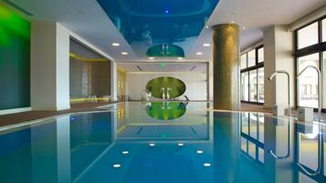 Una piscina interna con una visuale chiara del soffitto e delle pareti, un elemento decorativo centrale e una barriera in vetro.