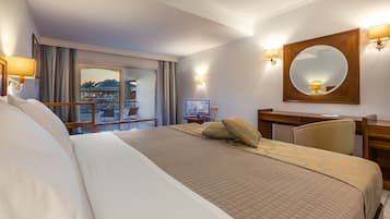 Habitación de hotel con una cama grande, un escritorio, una silla, un televisor y un balcón con vistas a la ciudad.