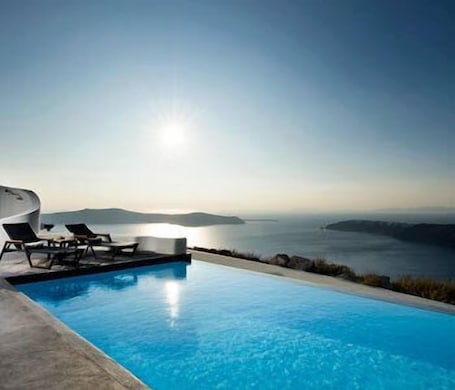 Una piscina al aire libre, sombrillas, sillones reclinables de piscina