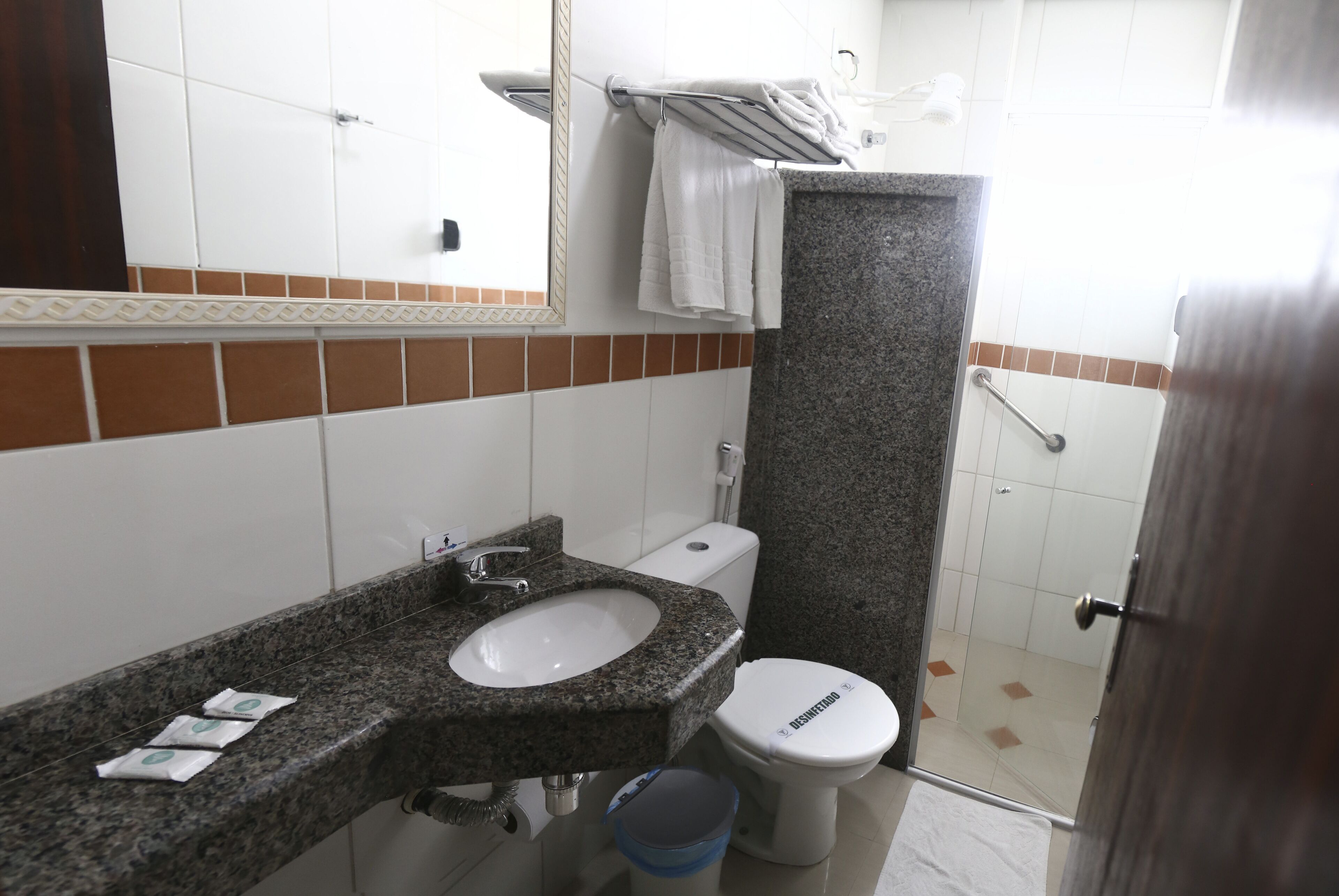 Een badkamer met een wastafel met granieten blad, een wit toilet en een douchegedeelte.