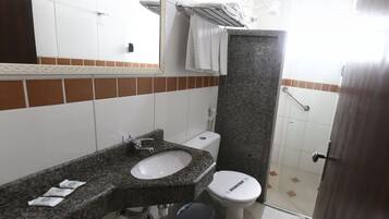 Een badkamer met een wastafel met granieten blad, een wit toilet en een douchegedeelte.