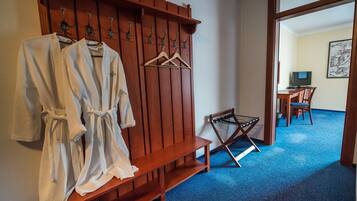 A hotel room with a wooden bench, a drying rack, and a desk with a chair.
