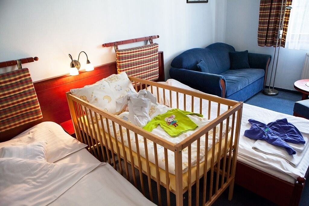 A room with a crib, a sofa, and a bedside table.