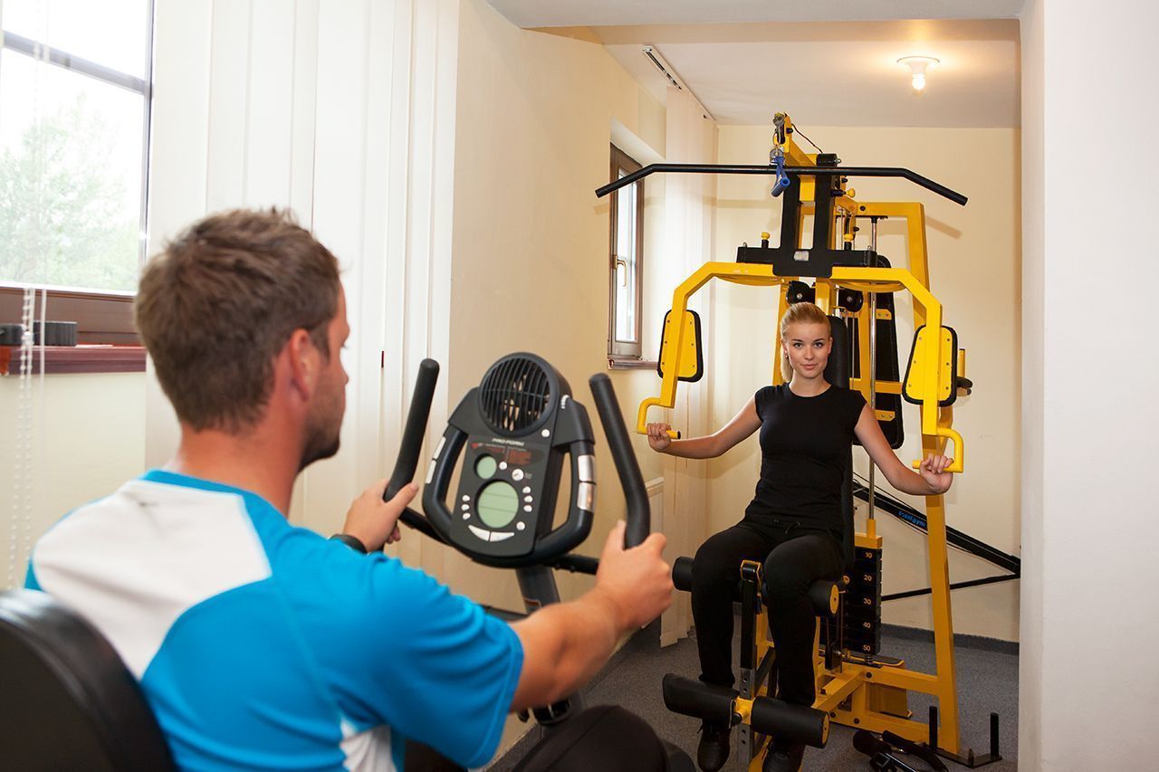 Ein Fitnessstudio mit Trainingsgeräten, darunter ein Ergometer und ein Kraftgerät.