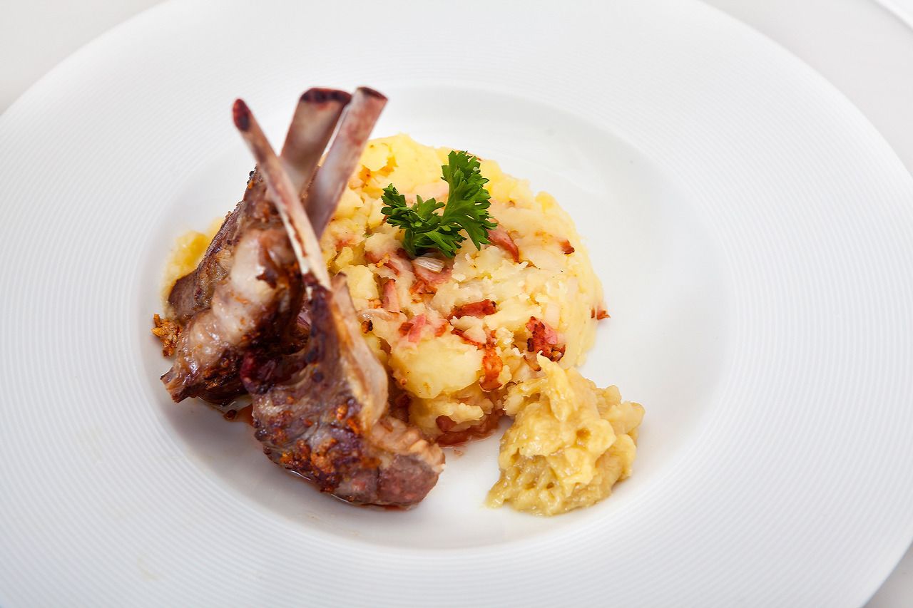 A plate with lamb chops and mashed potatoes garnished with parsley.