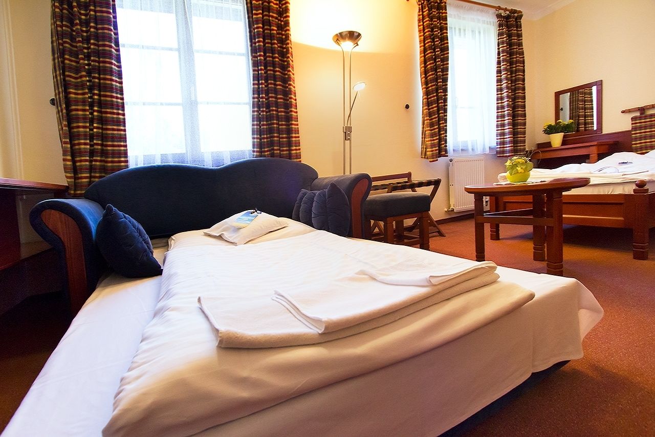 Une chambre d’hôtel avec un lit, un bureau, une chaise et une lampe sur pied.