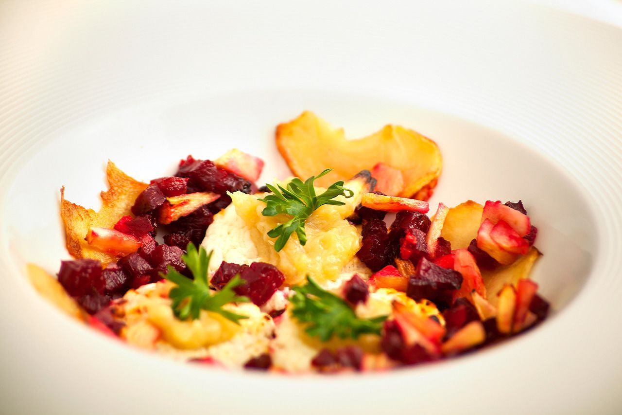 A white plate with a salad consisting of diced fruits and vegetables, garnished with parsley.