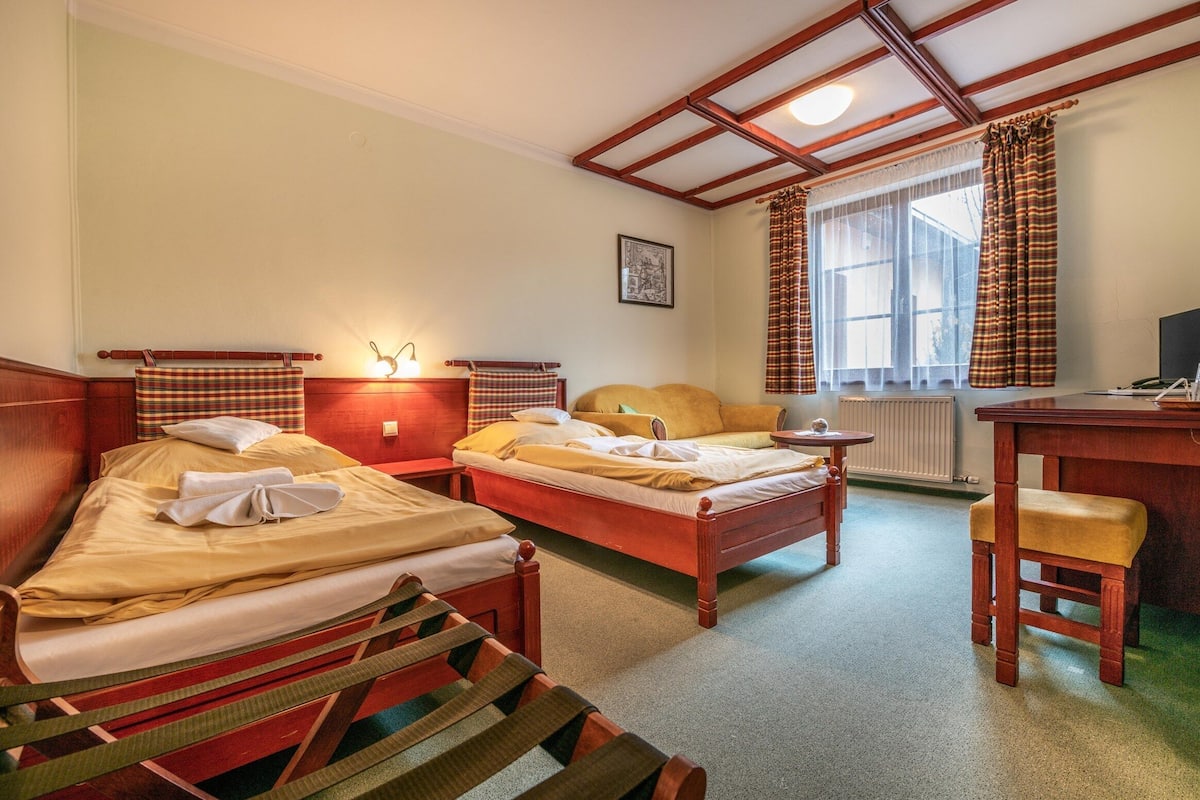 A hotel room with two beds, a desk, and a chair.