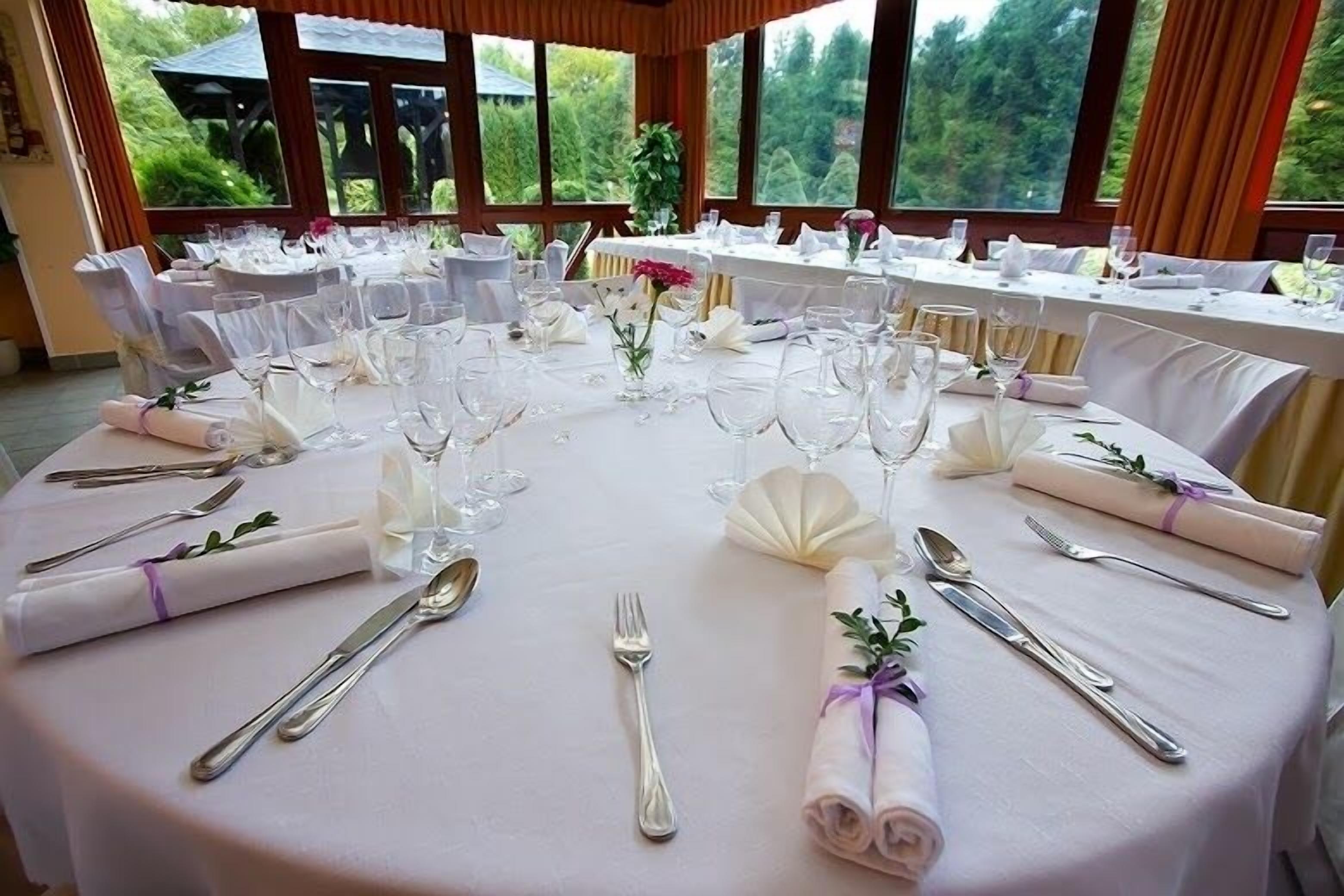 A round table set for a formal event with white tablecloths, folded napkins, and silverware.