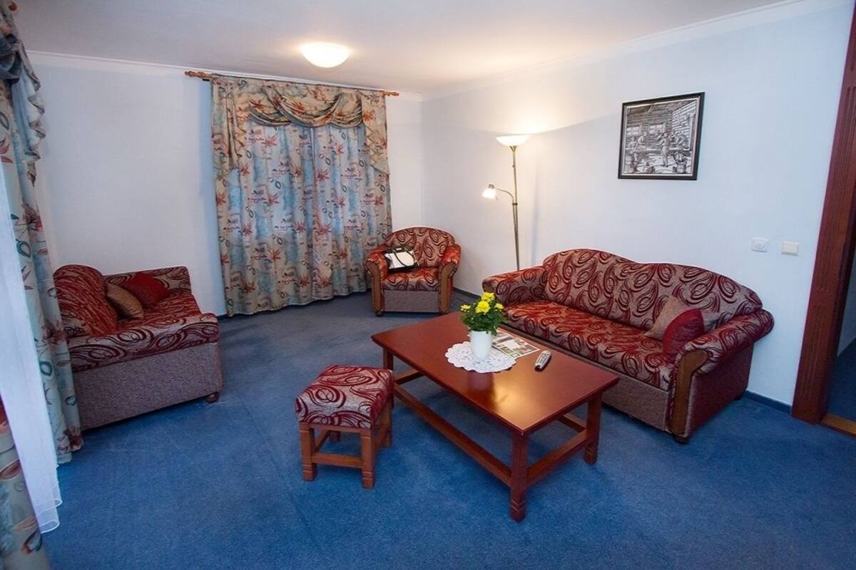 A living room with a sofa, armchair, and ottoman, a coffee table with a vase, and a floor lamp.