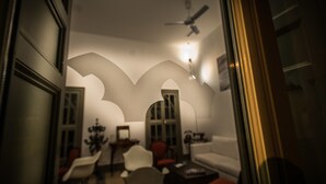Une pièce faiblement éclairée, dotée d’un aménagement intérieur moderne, comprenant un canapé, des fauteuils et un ventilateur de plafond.