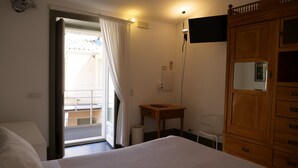 Une chambre à coucher avec un lit, une armoire en bois, un bureau et un téléviseur.
