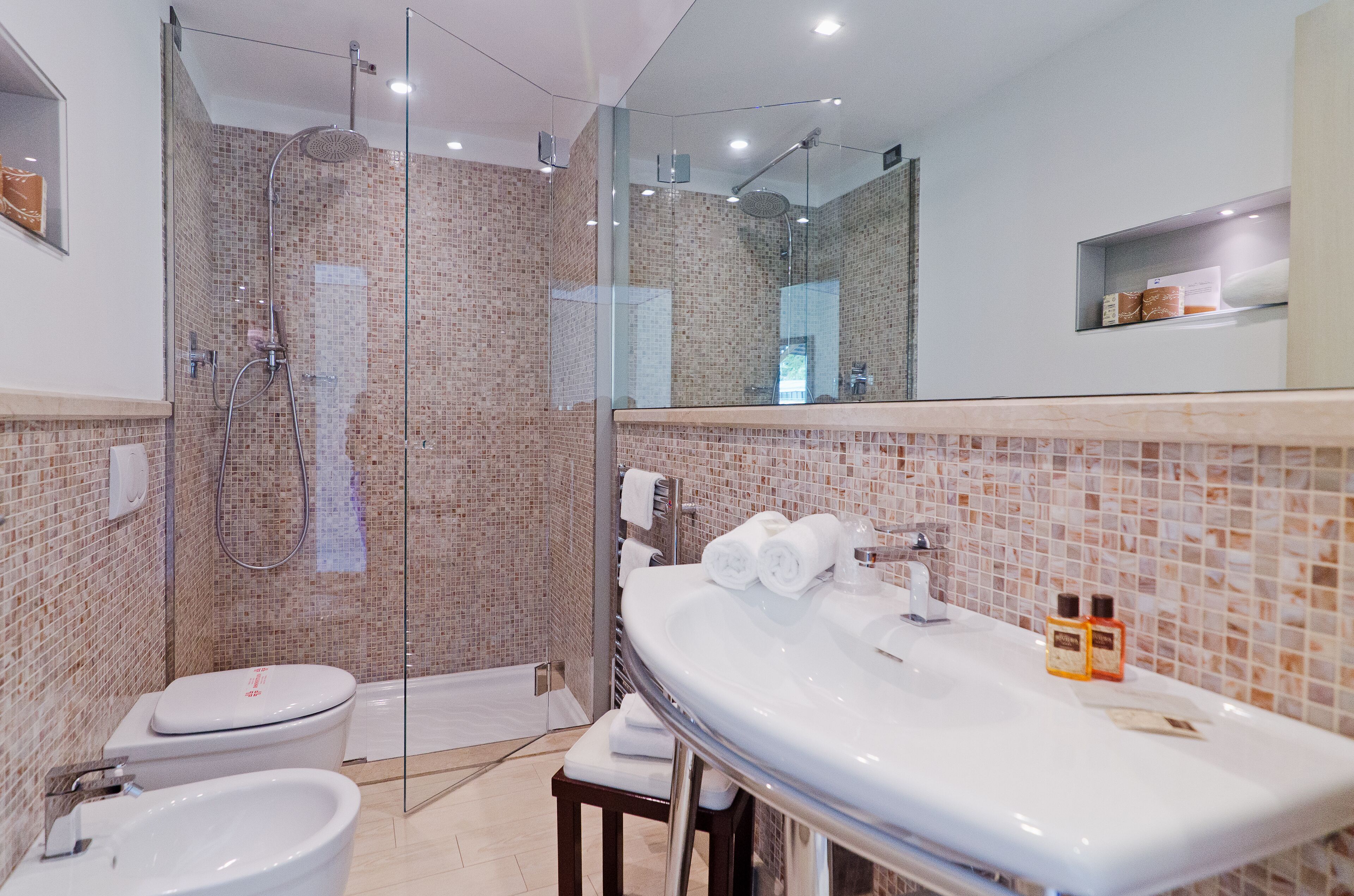A modern bathroom with a glass-enclosed shower, a large sink, and a toilet.