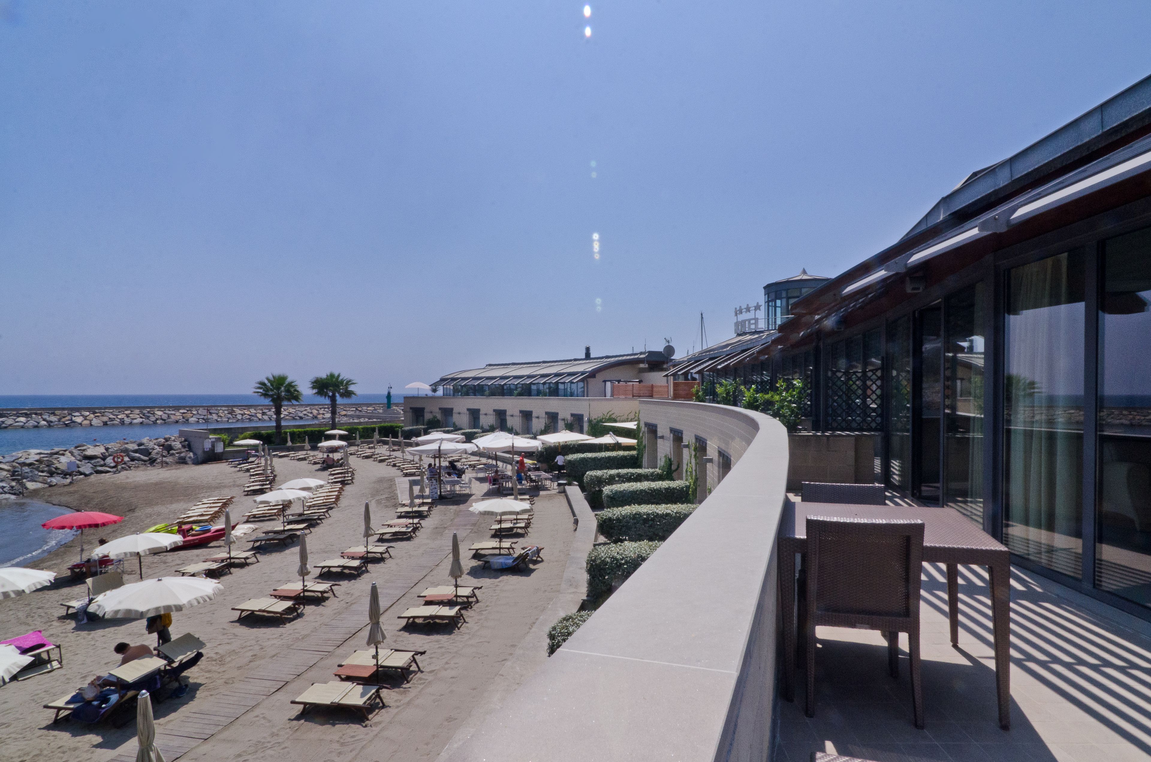 Un hotel frente a la playa con terraza, piscina y vistas al mar.