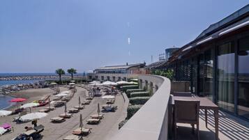 Un hotel frente a la playa con terraza, piscina y vistas al mar.