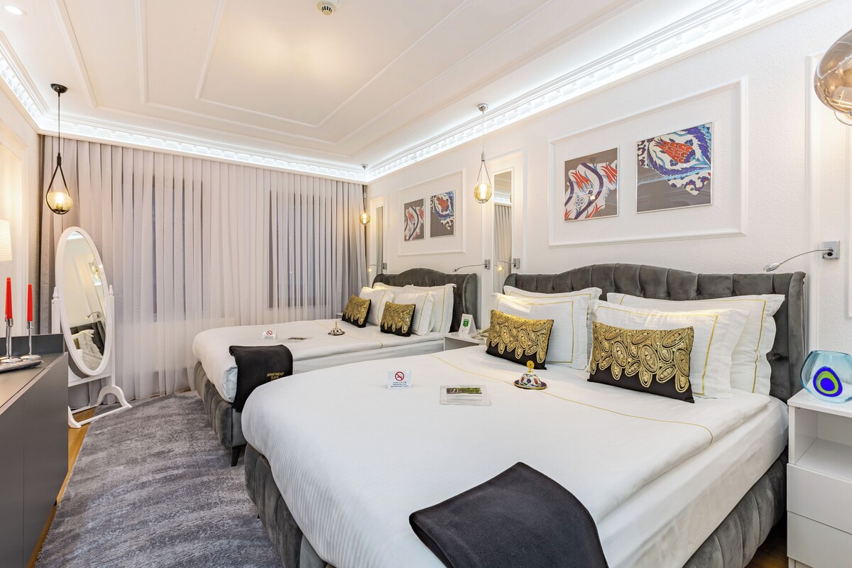 A hotel room with two beds, a large mirror, and artwork on the walls.
