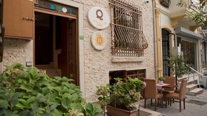 L’entrée d’un hôtel, avec une façade en pierre, un portail en fer forgé et des sièges à l’extérieur.