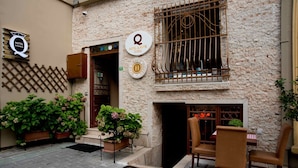 L’entrée d’un hôtel, avec un portail en fer forgé, un balcon orné d’une balustrade en fer forgé et des plantes en pot.