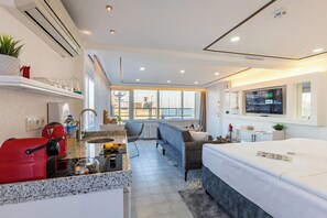 Une chambre d’hôtel moderne équipée d’un coin cuisine, d’un canapé, d’un lit et d’une télévision.
