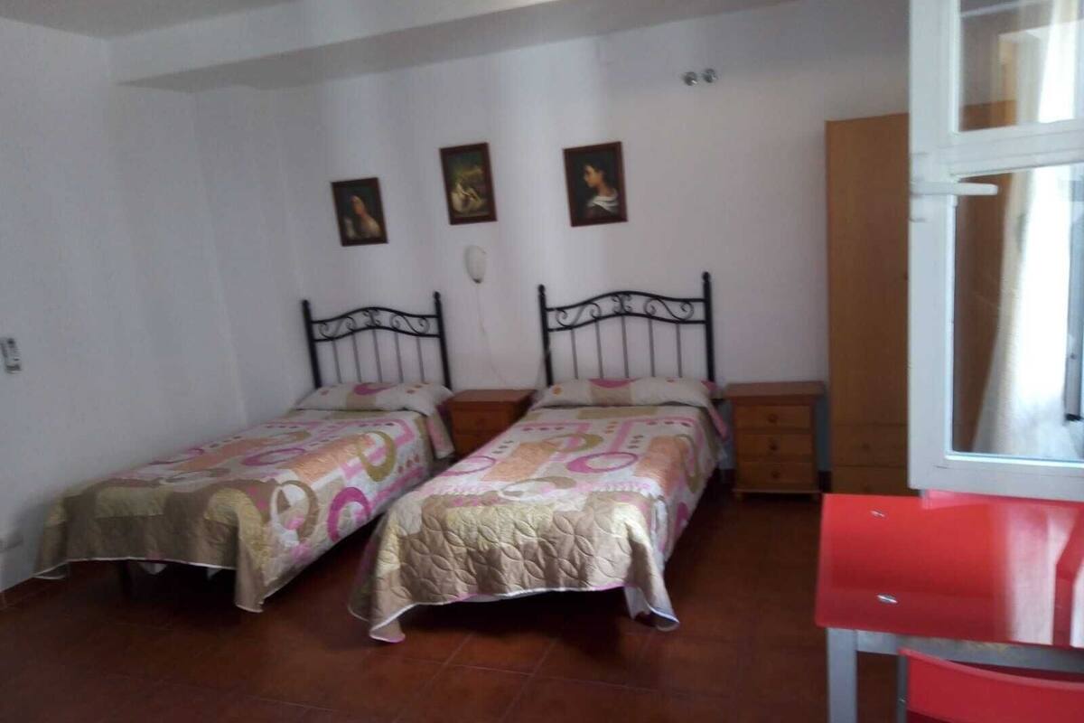 A bedroom with two beds, a wooden dresser, and a red chair.