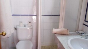A bathroom with a toilet, a shower, and a sink. - Alcázar (Córdoba)