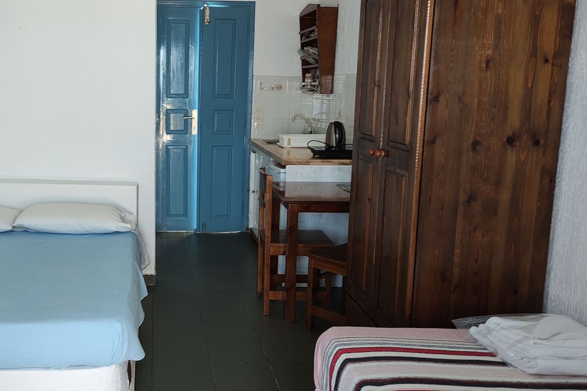 A bedroom with a bed, a desk, and a wardrobe.