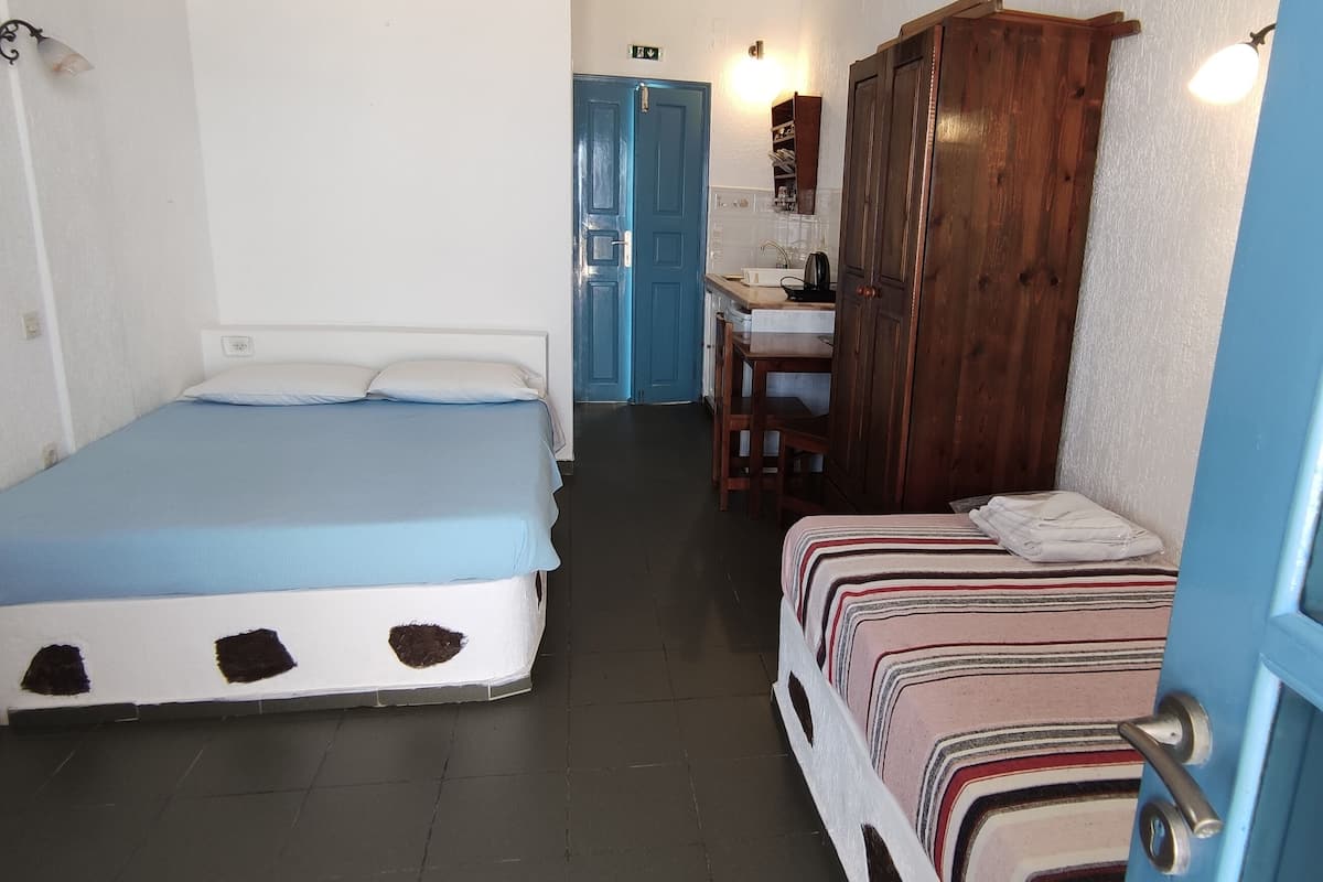 A small, compact room with a single bed, a small table, and a wardrobe.