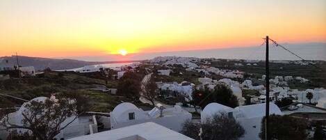 A coastal village at sunset with white buildings and a clear view of the sea.