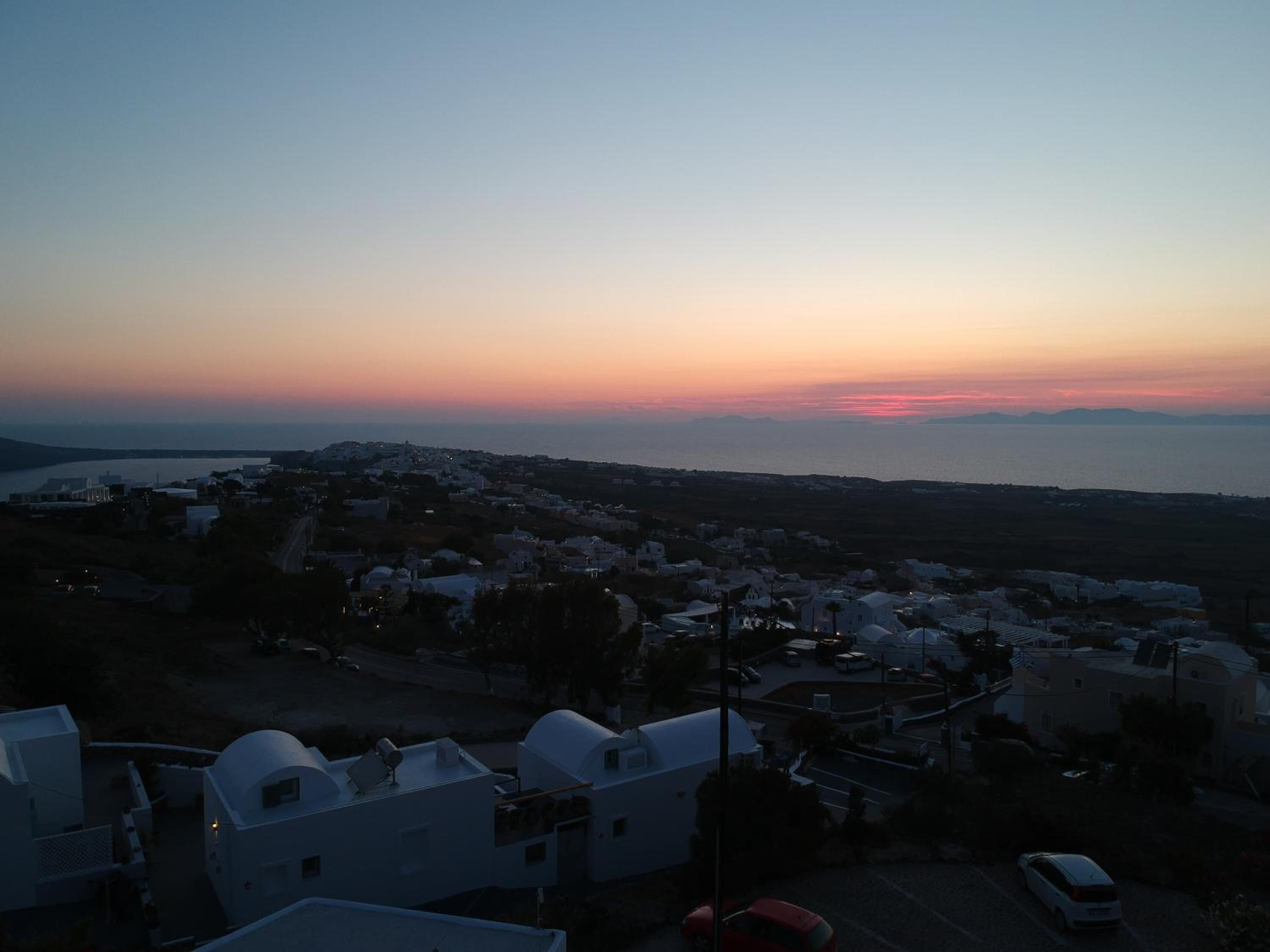 Un pueblo costero al anochecer con edificios blancos y vistas al mar.