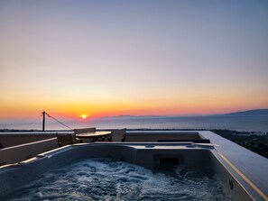 Una piscina en la azotea con vistas a la puesta de sol sobre el mar.