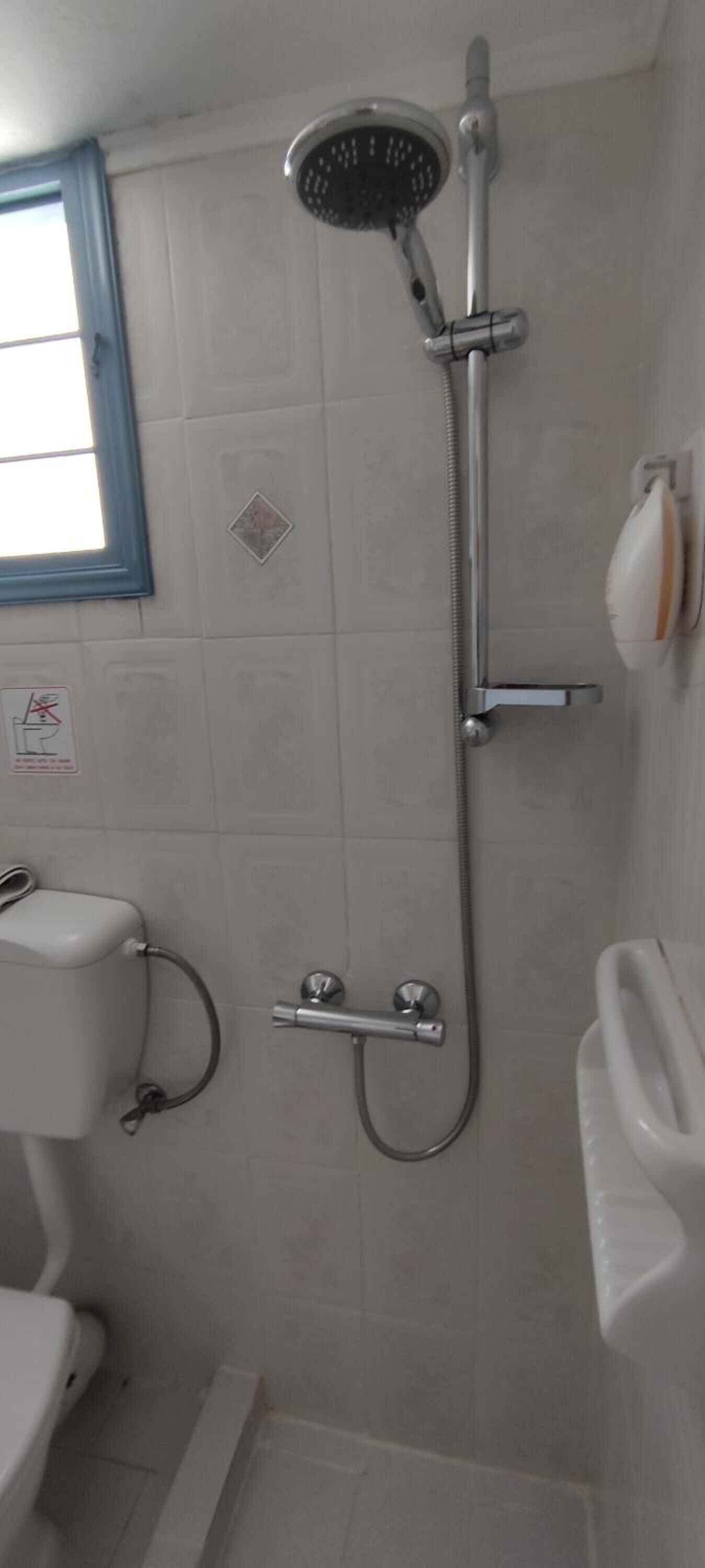 A small bathroom with a shower, toilet, and sink.