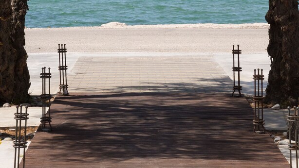A wooden pathway leading to a beach with a clear view of the sea. - The Wave (Corfu)
