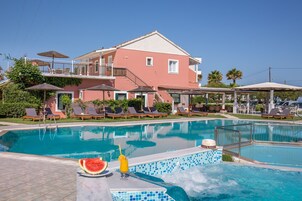 Un hotel con piscina, sillas de descanso y sombrillas.