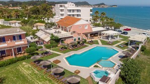 A resort with a large swimming pool, sun loungers, and a view of the sea. - The Wave (Corfu)