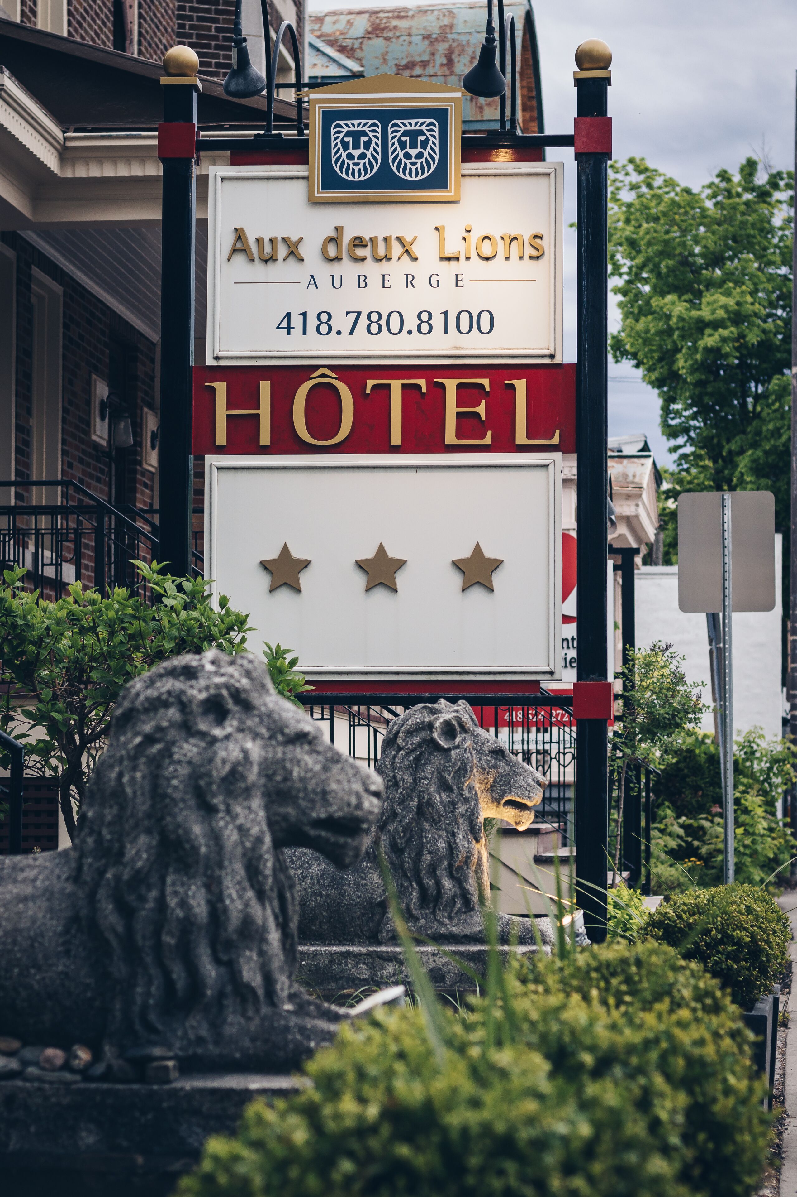Een hotelschilt met de naam 'Aux deux Lions' en een telefoonnummer.