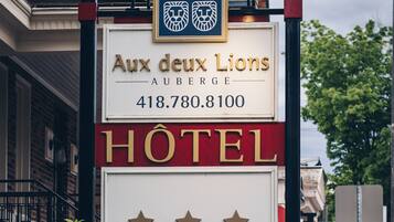 Een hotelschilt met de naam 'Aux deux Lions' en een telefoonnummer.