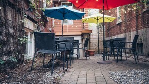 Un espace extérieur aménagé en patio, avec des murs en briques, des plantes en pot et du mobilier de jardin.