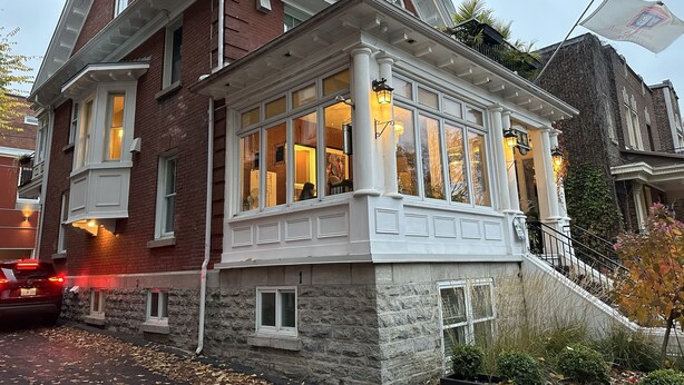 Un bâtiment de style victorien doté d’une baie vitrée, de fondations en pierre et d’un drapeau sur lequel on peut lire le mot « Auxiliaire ».
