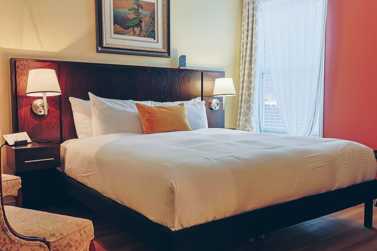 A neatly made bed with white linens, a wooden headboard, and two bedside lamps.